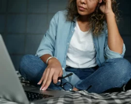 Woman sat on bed on laptop